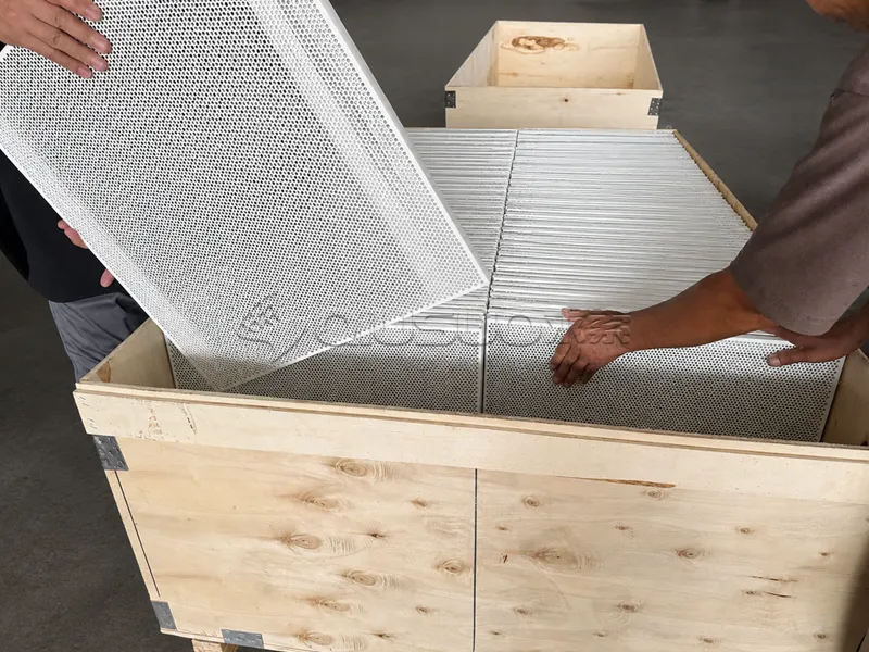 The aluminum perforated sheet products are being placed into wooden packaging boxes.