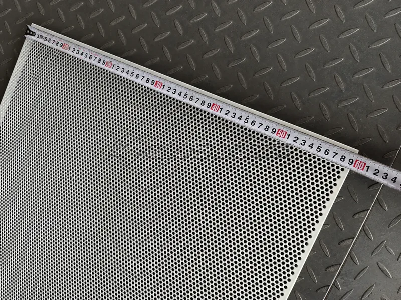 The size of the aluminum perforated sheet is being measured with a tape measure.