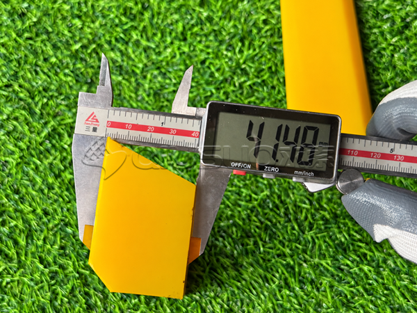 A worker is measuring the tapered end of a polyurethane wedge with a digital caliper.