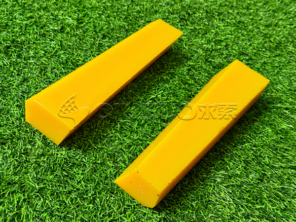 Two yellow polyurethane wedges are placed on the green grass.