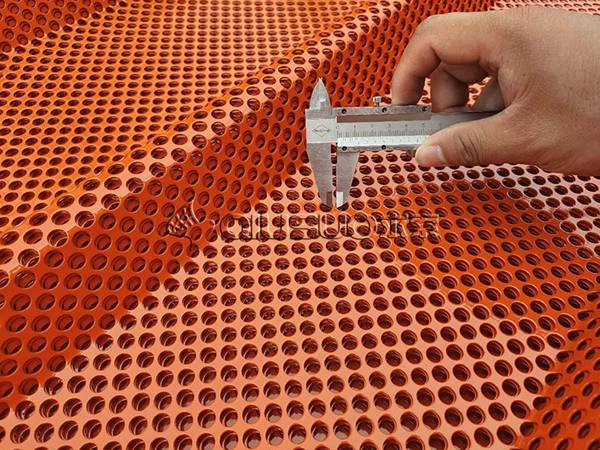 Un travailleur vérifie la taille du maillage pour les tôles perforées ondulées.