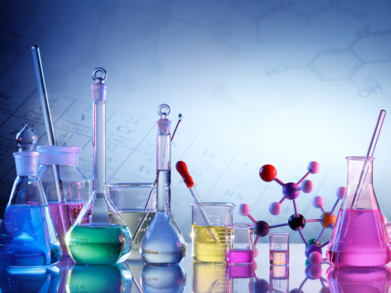 Multiple test tubes, conical flasks, and measuring cups are containing colorful reagents.