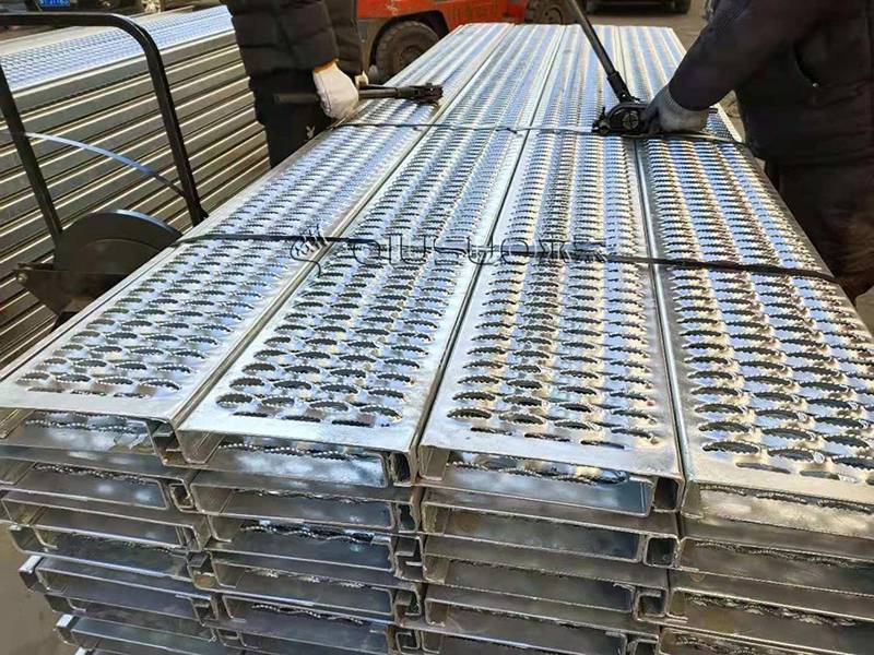 Two workers are packing diamond grip plank grating by steel belt.