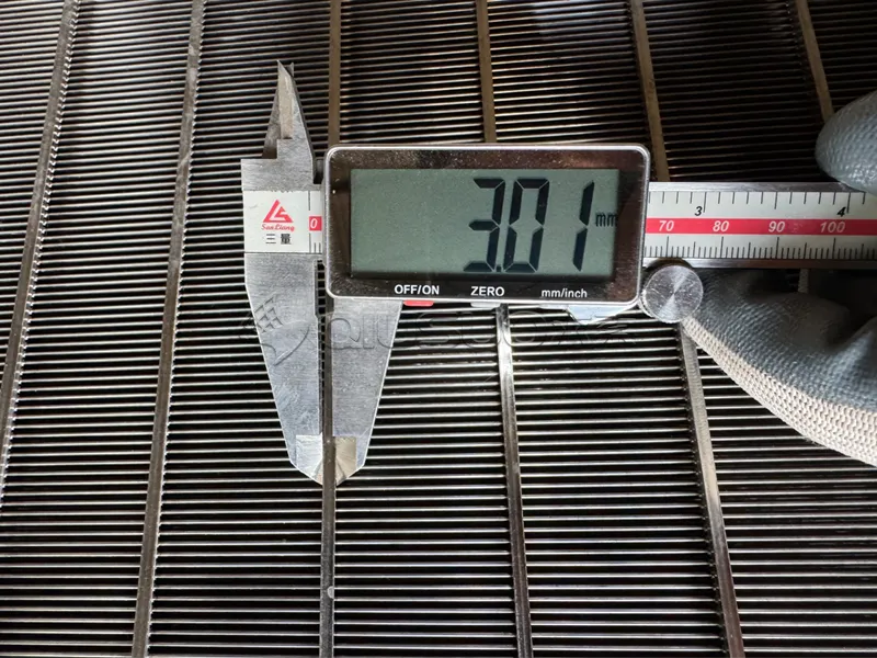 A worker is using a caliper to measure the size of the support rod of the flat wedge wire screen.