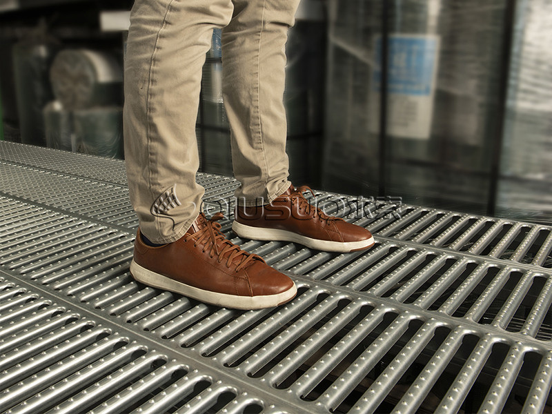 A man is waling on the working platform made of grate lock safety gratings.