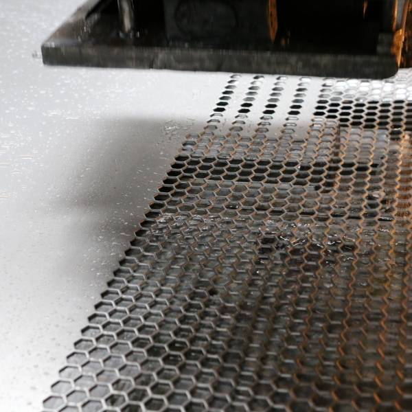 The CNC punching machine is punching holes on the metal plate.
