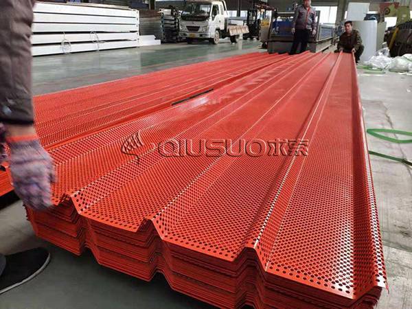 Trois travailleurs emballent des feuilles perforées à trous ronds orange