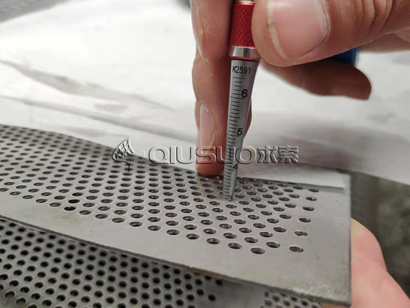 The worker is checking the hole size of the perforated metal.