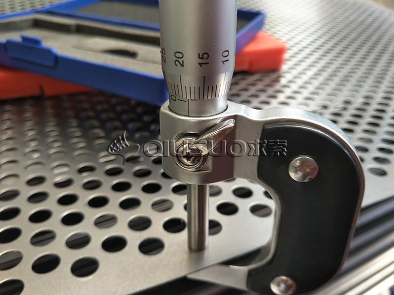 A micrometer is used to check the thickness of the perforated metal.