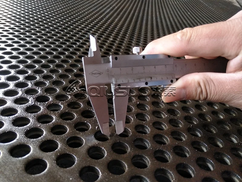 The worker is measuring hole pitch with a caliper.