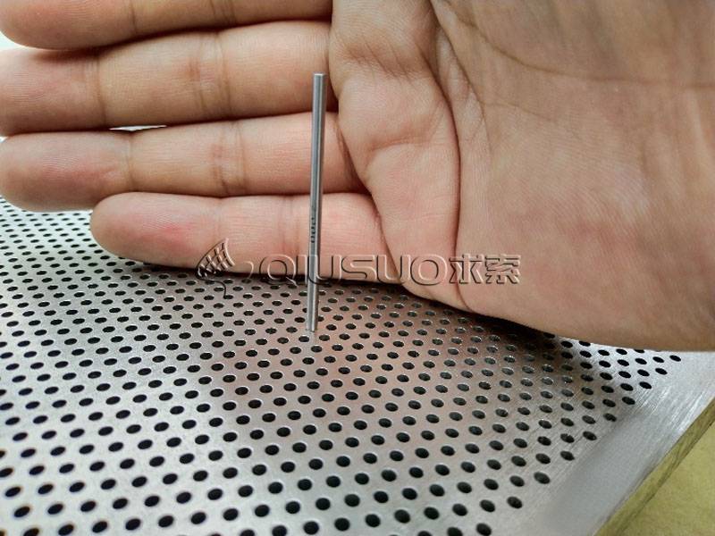 A hand is holding a rod to check stepping drilling perforated plates hole diameter.