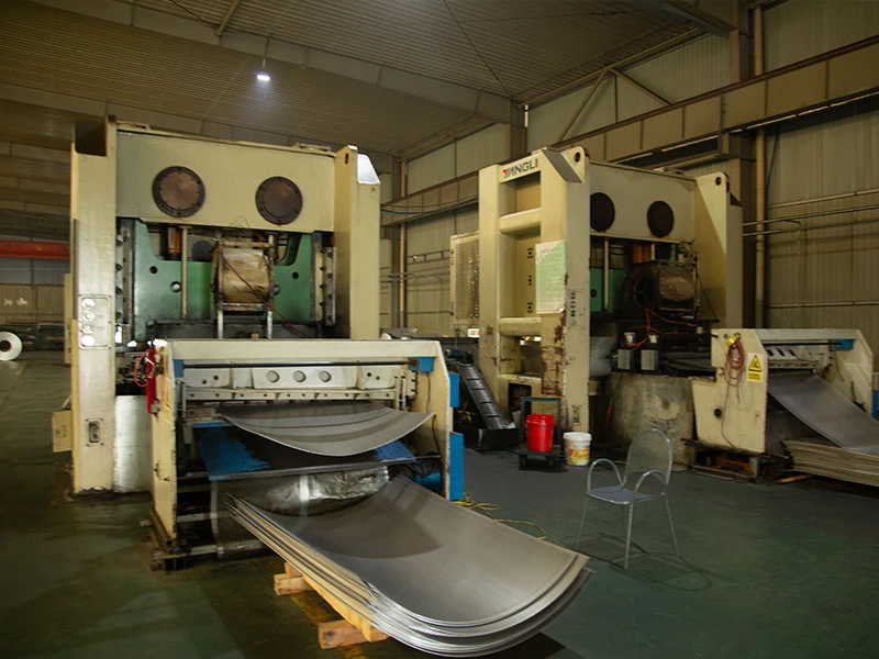 A metal sheet is being processed by a High-Speed Gantry Full-Width Perforating Machine.