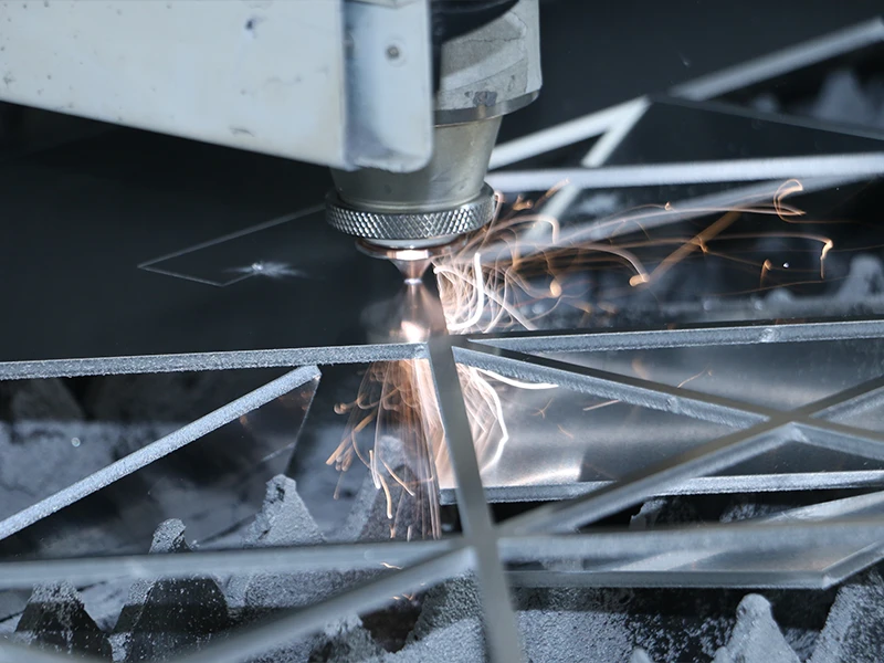 The metal sheet is being cut into triangular patterns using a laser cutter.