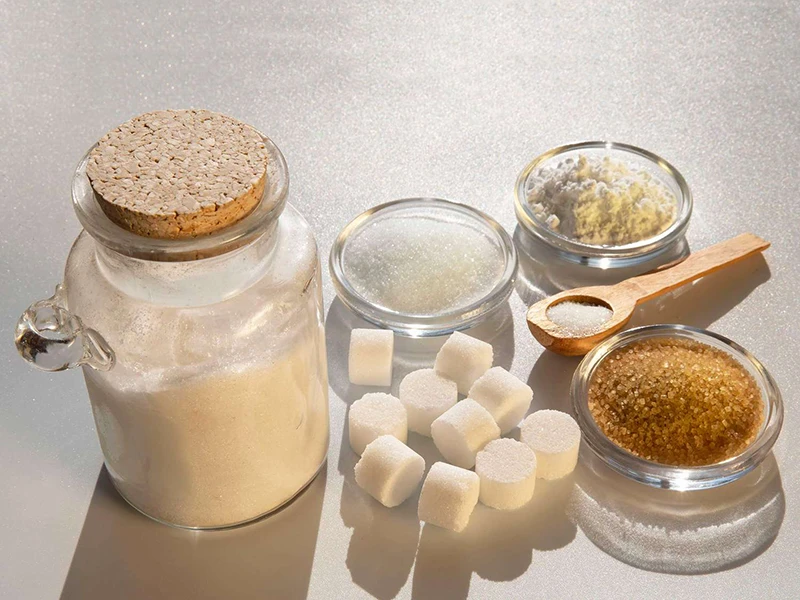 Bir mason kavanozu ve üç kase toz şeker içerir ve silindirik şeker küpleri masaya yerleştirilir