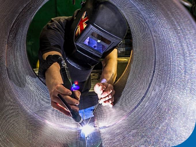 The worker is welding the wedge wire screen from inside.
